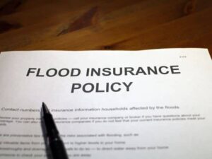 Flood insurance policy document with pen on desk representing Elevation Certificate verification for flood insurance qualification and review.